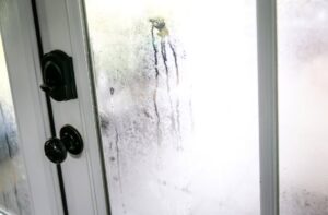 Condensation and moisture buildup cover a glass exterior door.